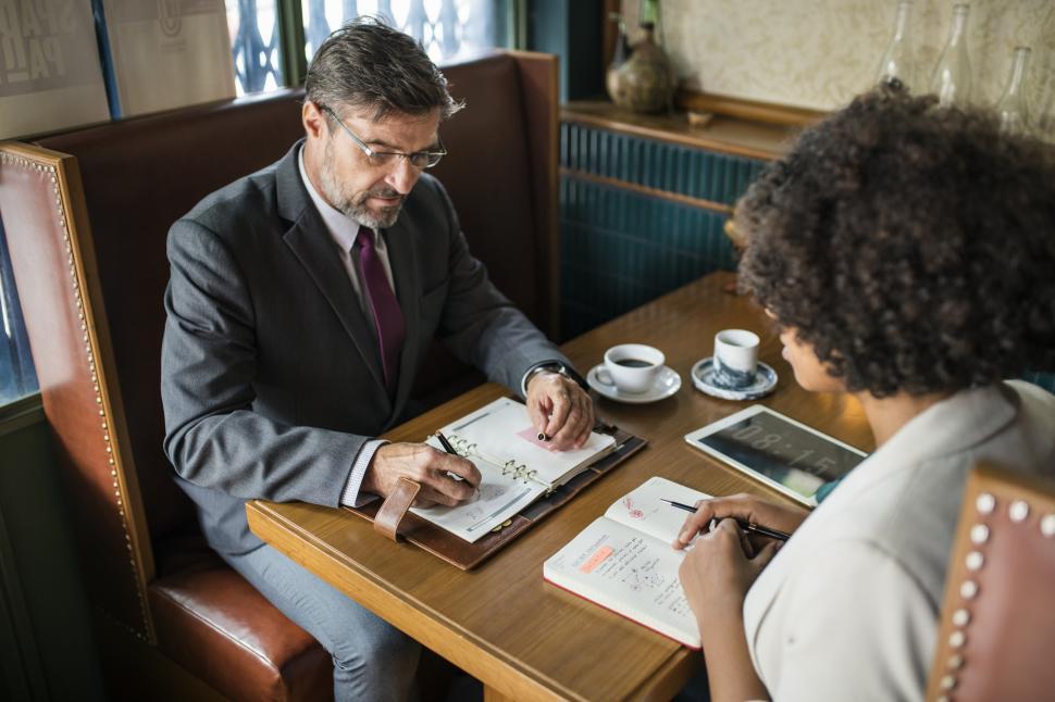 Free Image of A senior Caucasian man sits with a colleague at a cafe 