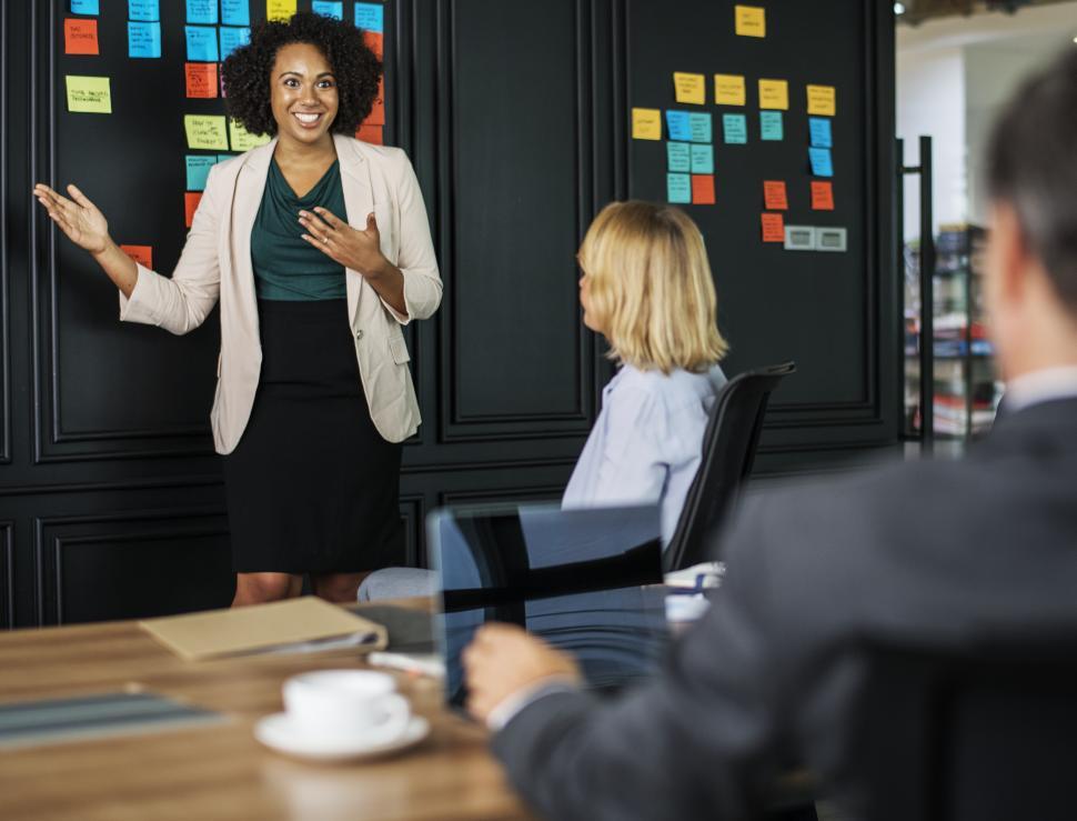 Free Image of A smiling young woman presenting in a business meeting 