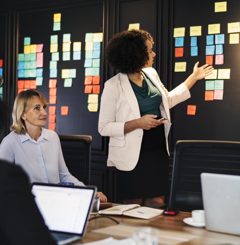 Free Image of A young woman presenting notes in a business meeting 