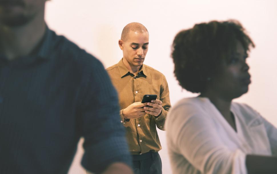 Free Image of A man behind a crowd looking at his mobile phone screen 
