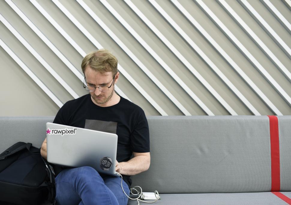 Free Image of A young man sitting on a bench working on his laptop 