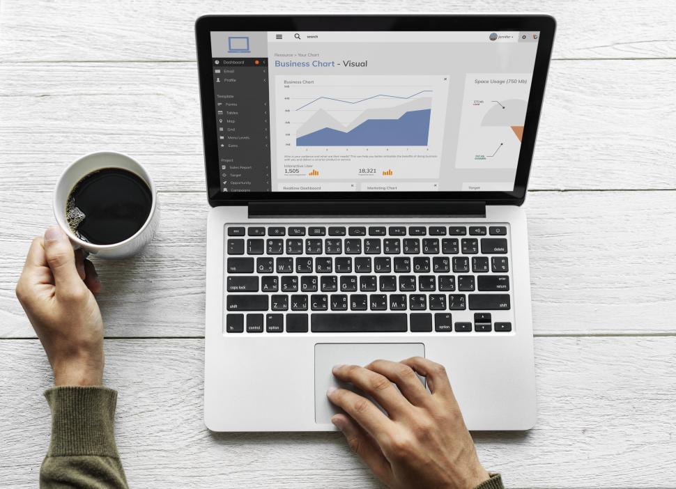 Free Image of Overhead view of a hand on a laptop and a hand on coffee 