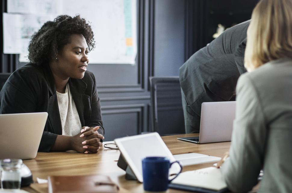 Free Image of A young woman in a meeting, listening to colleagues  