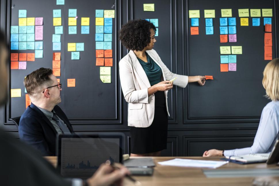 Free Image of A young woman in a business meeting, using sticky notes to demonstrate  