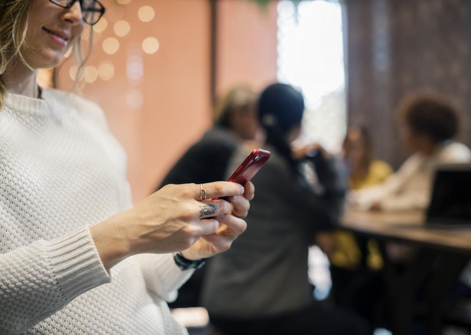 Free Image of A smiling young Caucasian woman looks at her mobile 