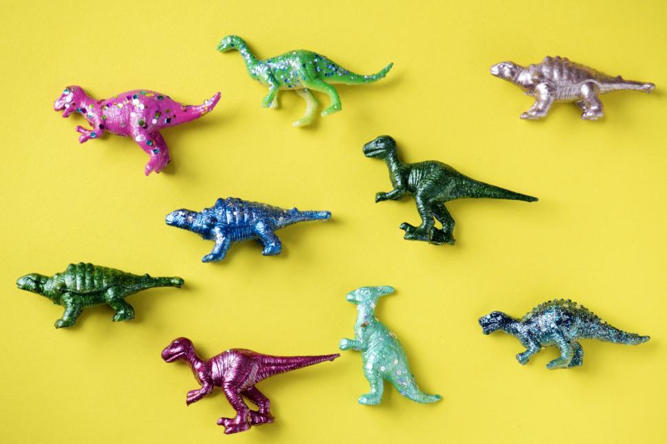 Free Image of Colorful toy dinosaurs on yellow surface 
