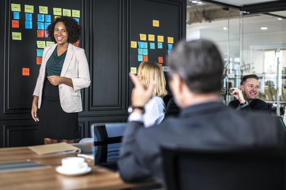 Free Image of A smiling young woman presenting in a business meeting 