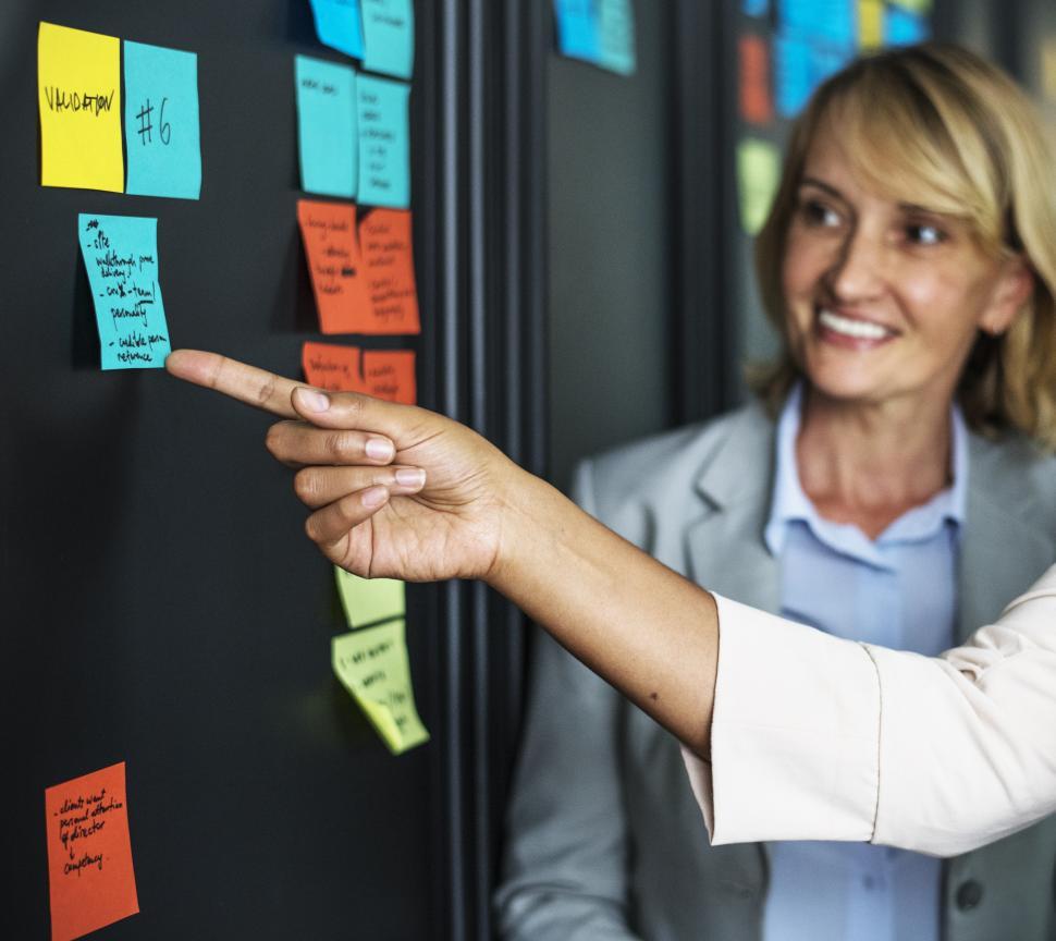Free Image of A woman looks at sticky notes on the project board 