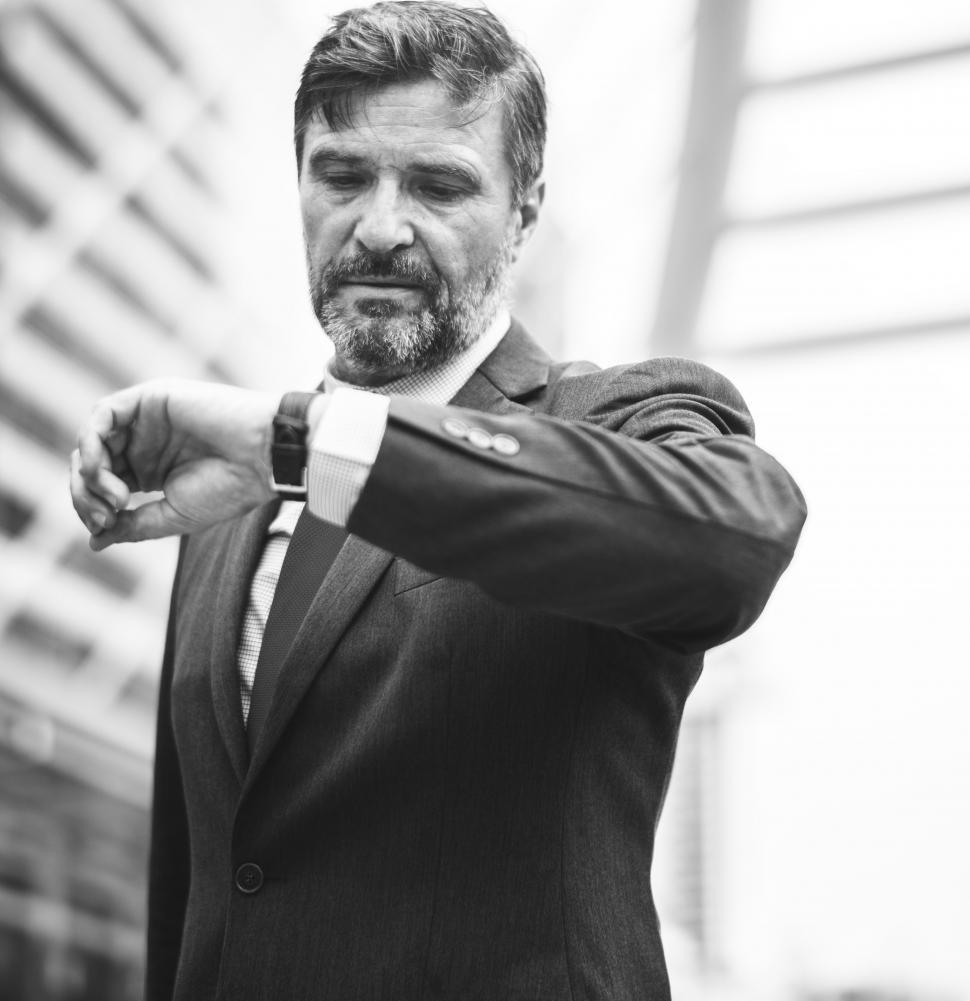 Free Image of A bearded businessman looks at time - black and white 
