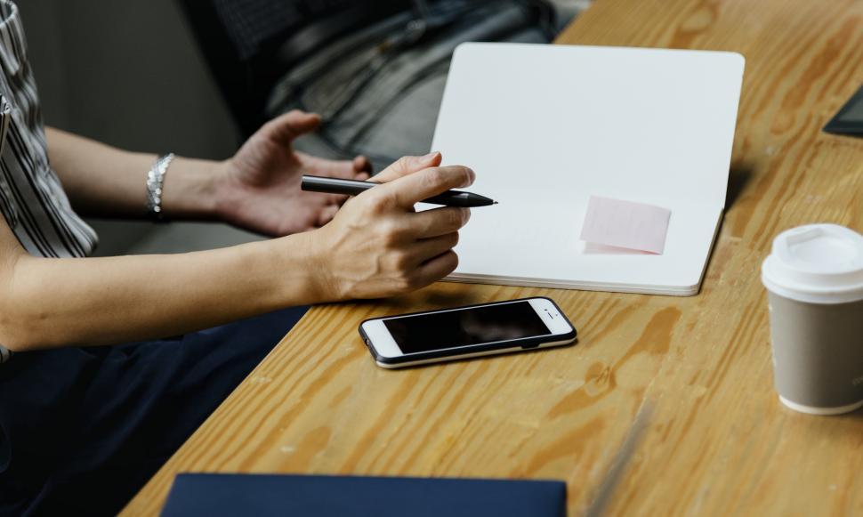 Free Image of Close up of a woman s hand holding a pen to write on the notebook 