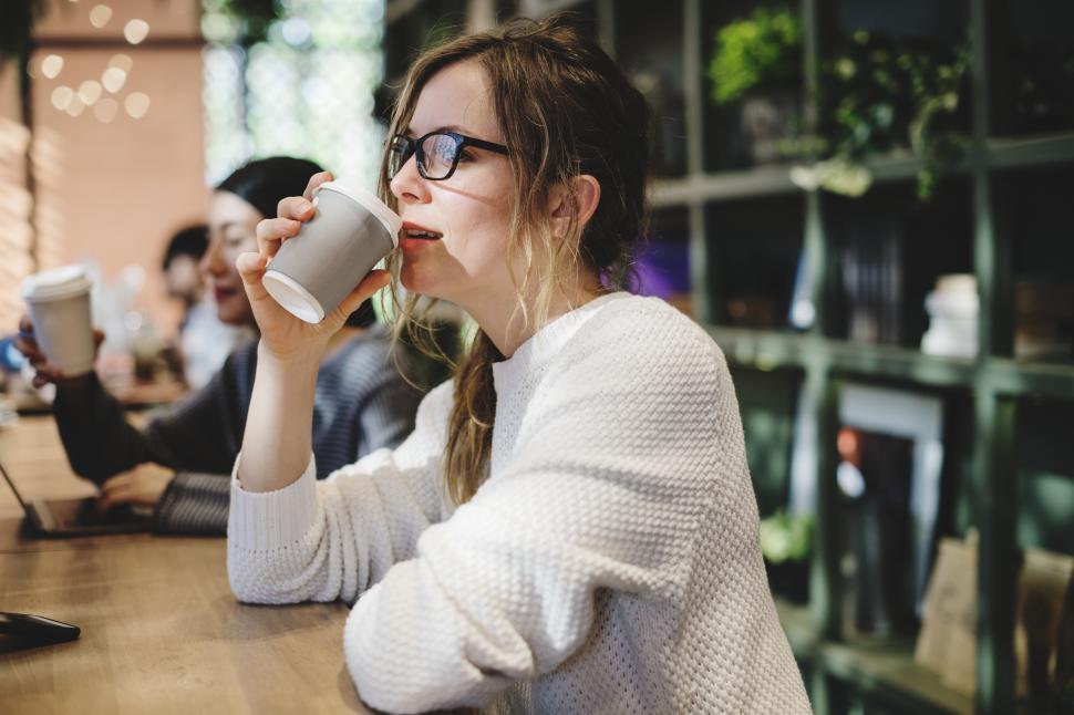 Free Image of A young Caucasian woman enjoying coffee at a cafe 