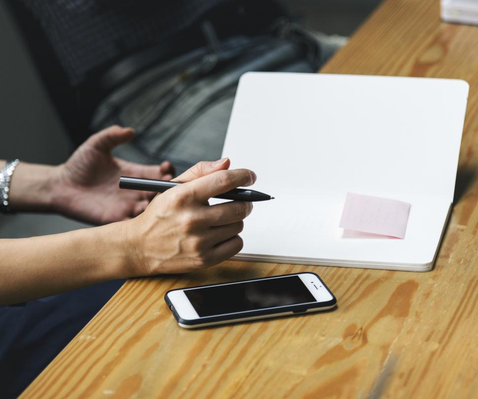 Free Image of Close up of a woman s hand holding a pen to write on the notebook 
