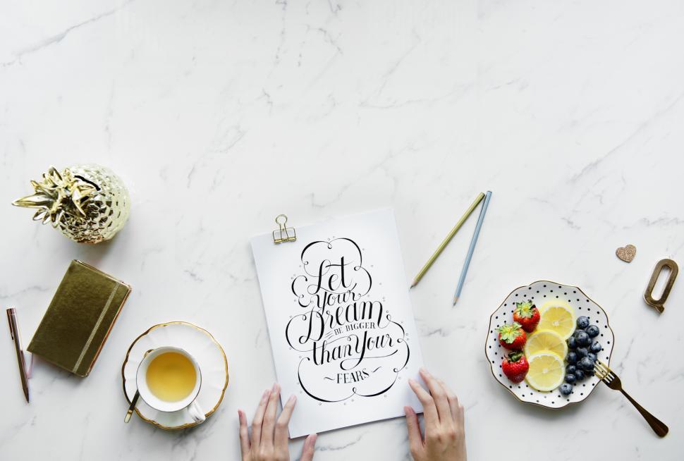 Free Image of Overhead view of hands on a sheet of paper with a motivation quote 