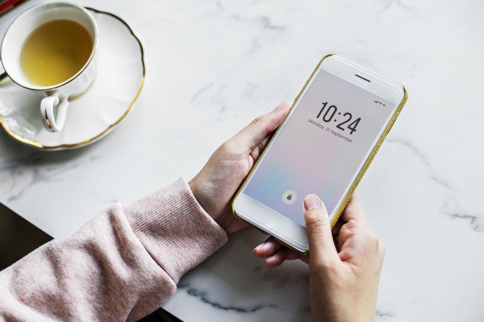 Free Image of Close up of a smart phone in a person s hands, with cup of tea 