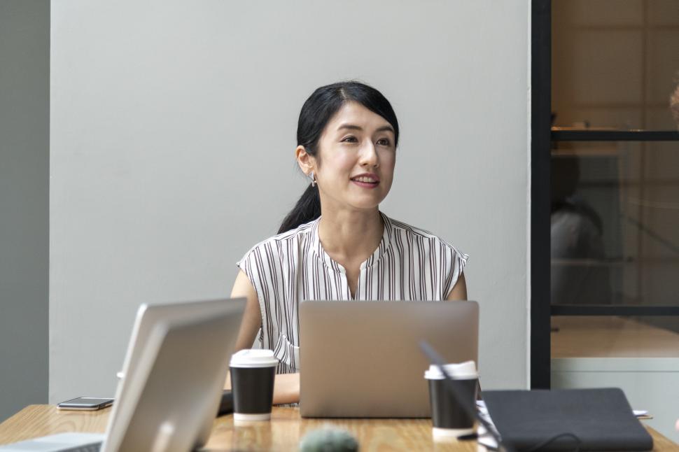 Free Image of A woman in the office sitting at a laptop computer 