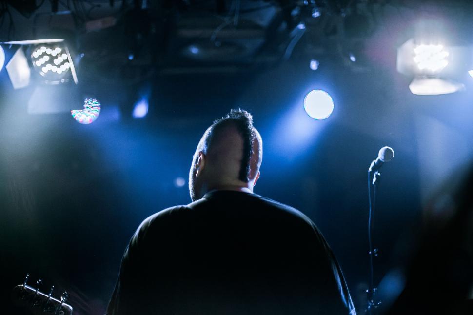 Free Image of Man Standing in Front of Microphone on Stage 