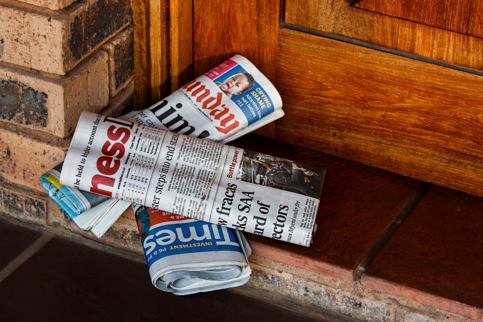 Free Image of Newspaper Laying Next to Door 