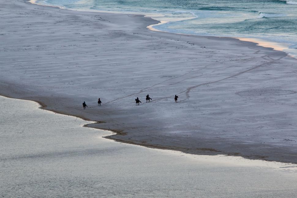 Free Image of Group of People Walking Along Beach by the Ocean 