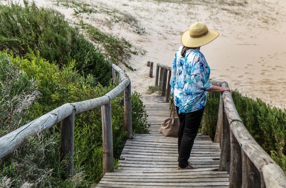 Free Image of Woman in Hat Walking Up Wooden Staircase 
