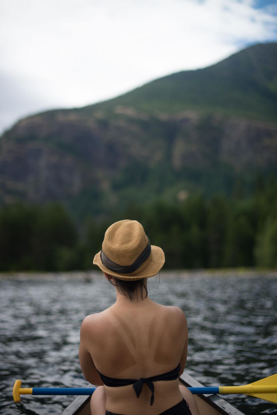 Free Image of Back View of Woman on boat with river and mountains in the background 