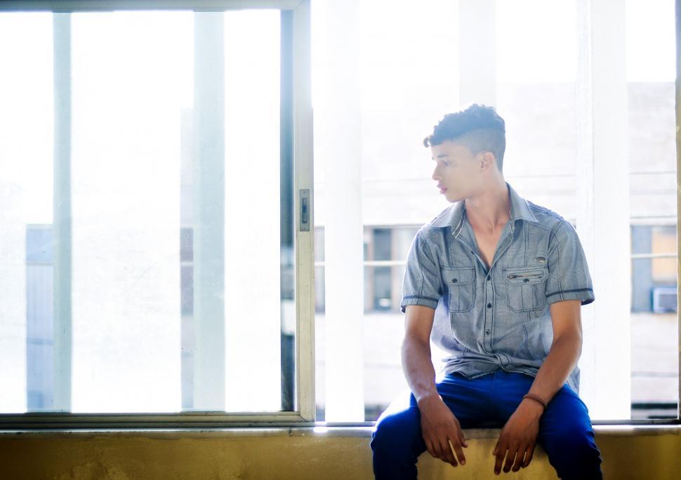 Free Image of Young Man sitting near window 