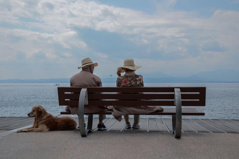 Free Image of Old elderly couple sitting on bench by beach 