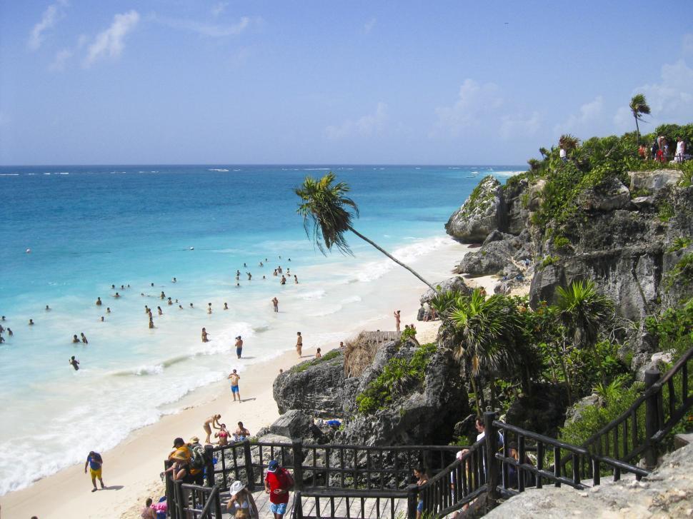Free Image of People on Beach With Rock Cliff and Trees  