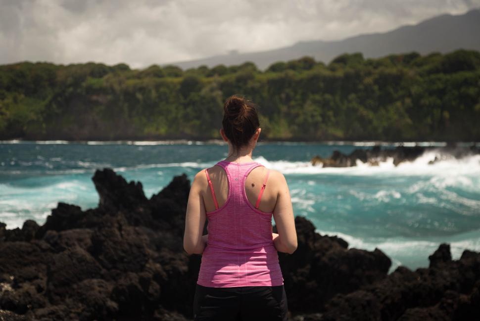 Free Image of Woman Standing on rock near ocean  