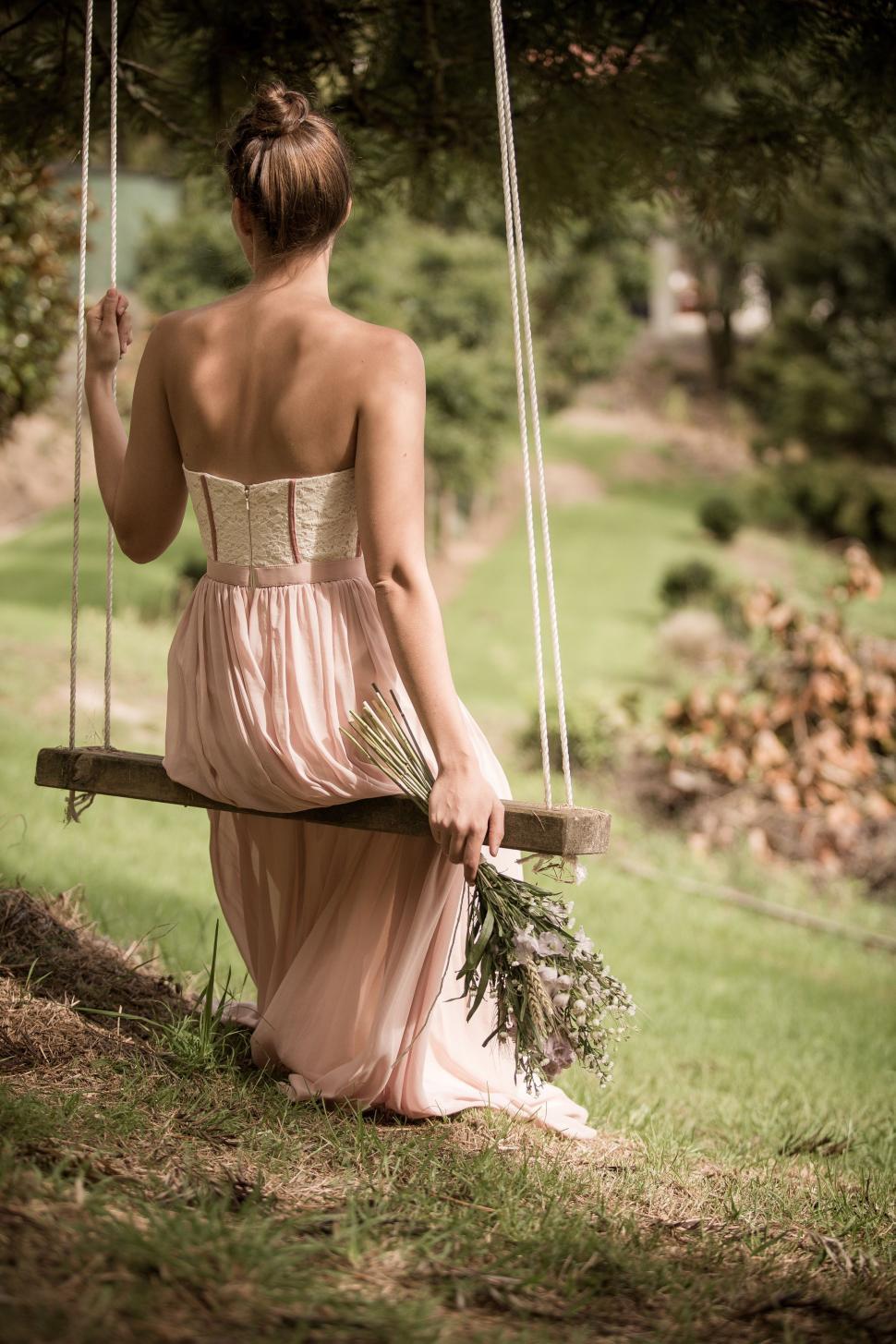Free Image of Woman on swing holding flower bouquet 