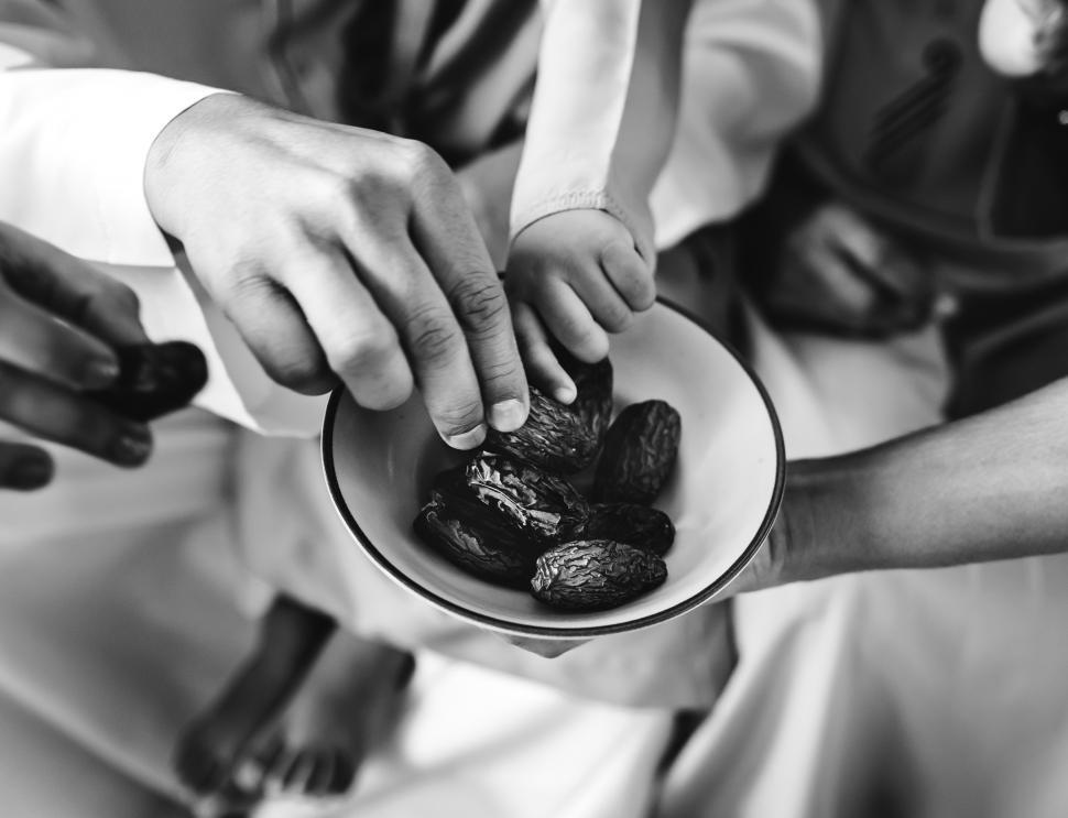 Free Image of Black and white photo of people sharing a bowl of dates 