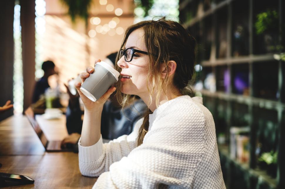 Free Image of A young Caucasian woman enjoying coffee at a cafe 