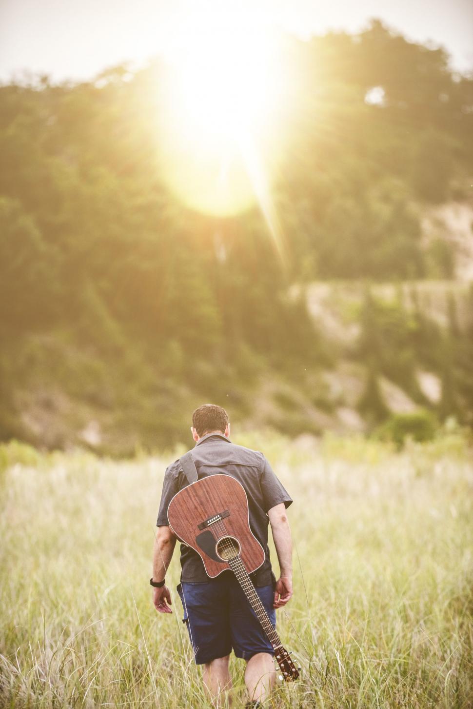Free Image of Back Side View of Guitarist in grass field 