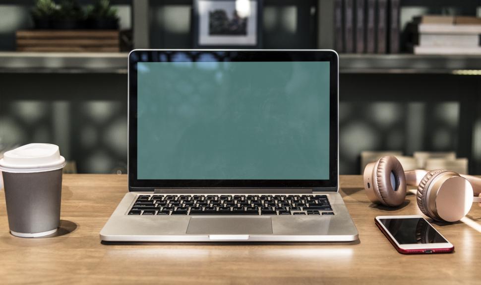 Free Image of A blank screen laptop surrounded with a disposable coffee mug and a smart phone 