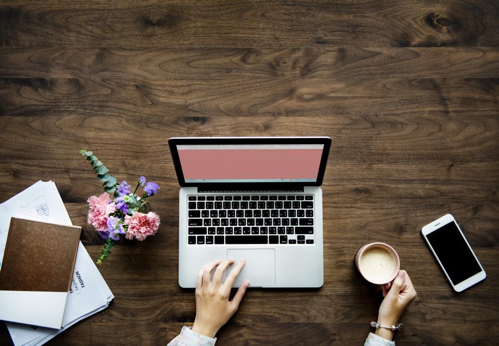 Free Image of Copyspace - Overhead view of a laptop and a woman s hand holding a coffee mug 