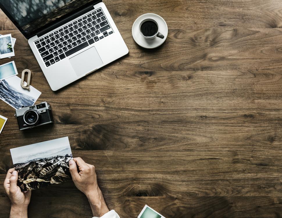 Free Image of Overhead view of a hand holding a picture with copyspace and wooden texture 