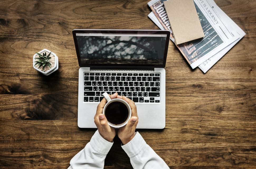 Free Image of Overhead view of hands holding a coffee mug in a workspace 
