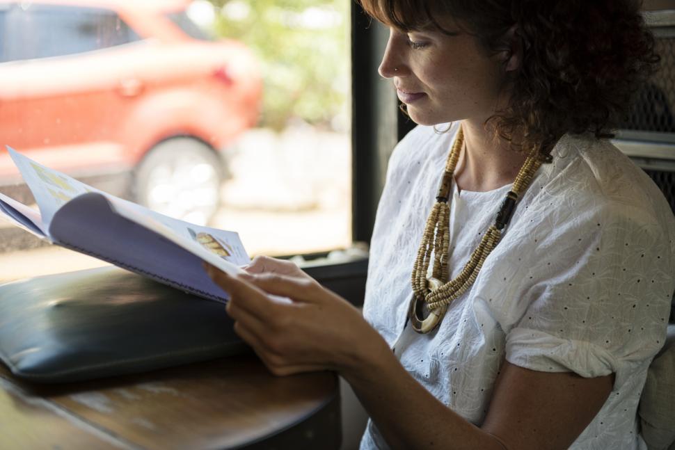 Free Image of A young woman reading menu at a restaurant table 
