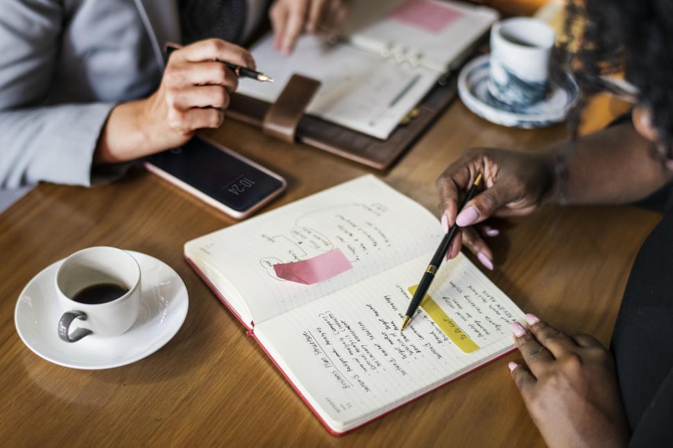 Free Image of Anonymous womans hand taking notes at a cafe table 