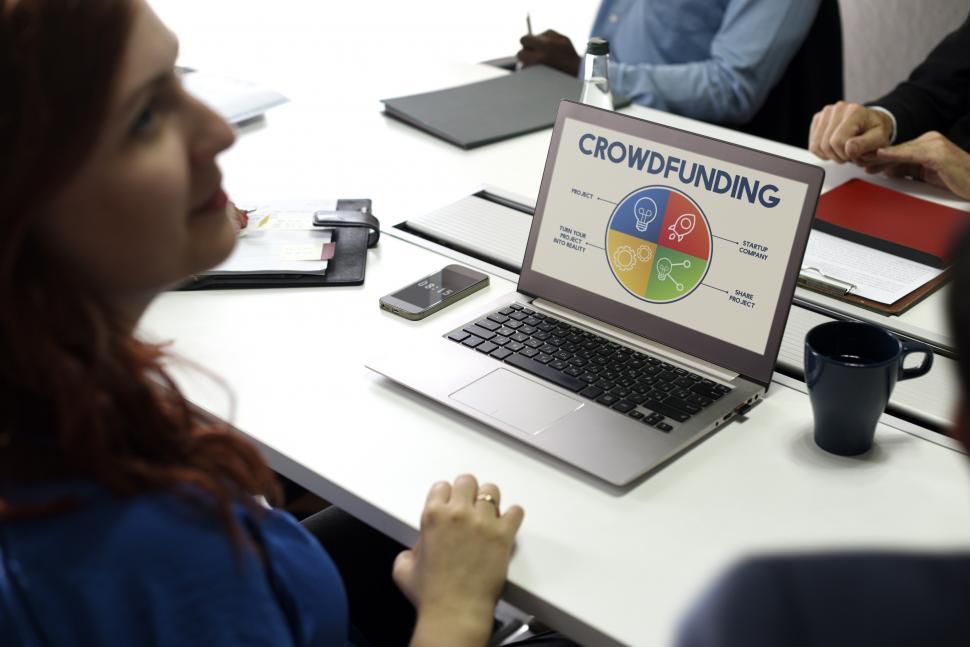 Free Image of Over the shoulder view of a laptop on the table with crowdfunding graphic 