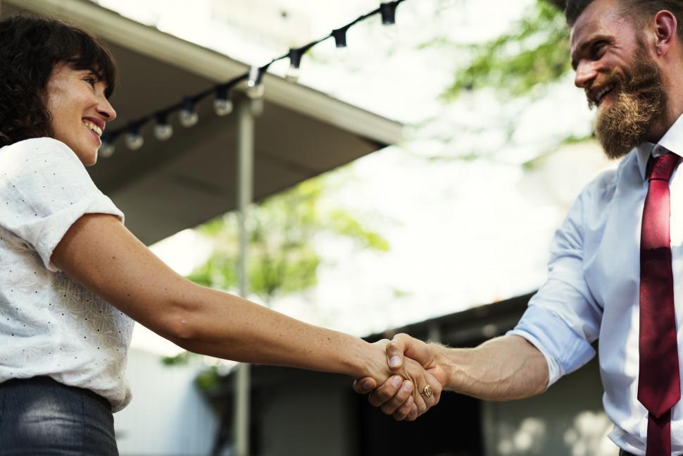 Free Image of Two people shaking hands, standing outdoors 