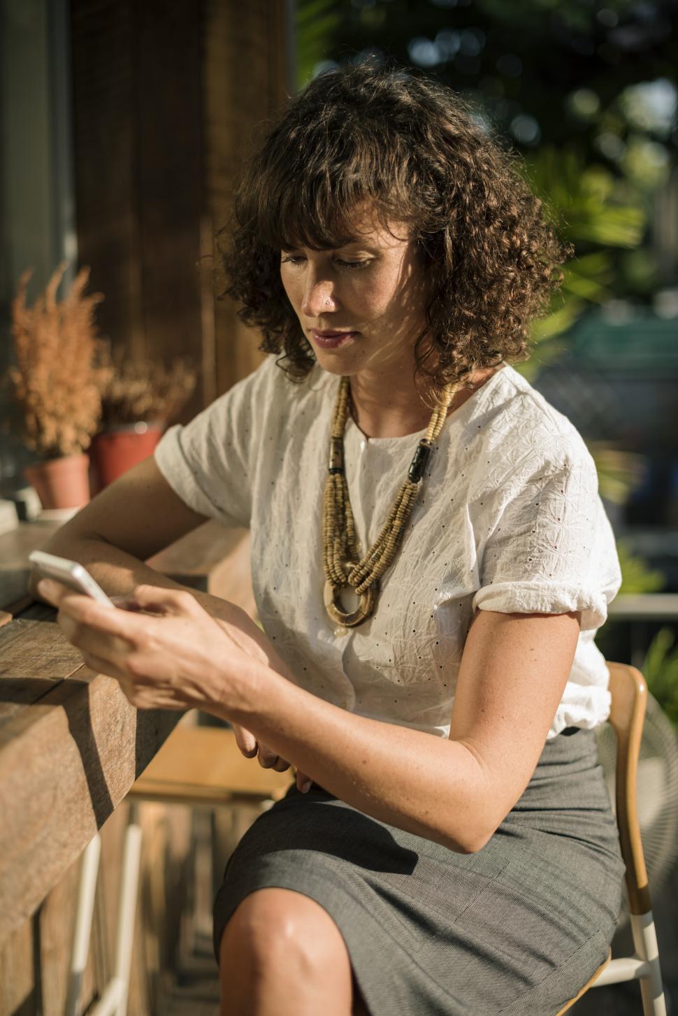 Free Image of A young woman sitting outside looking at her mobile phone 