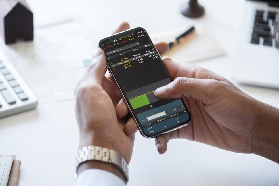 Free Image of Hands operating a mobile phone with stock prices 