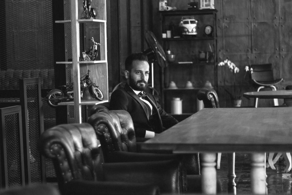 Free Image of Young Man in Black Suit Sitting Inside a Restaurant - B&W 