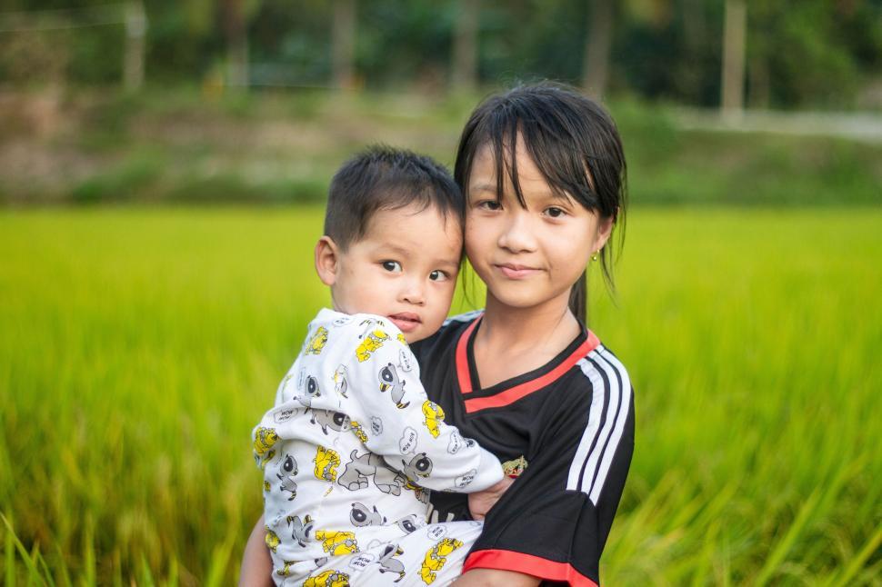 Free Image of Young Girl holding her little brother in her arms 