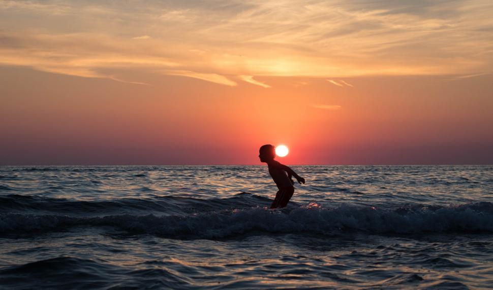 Free Image of Boy in Ocean With Sunset  