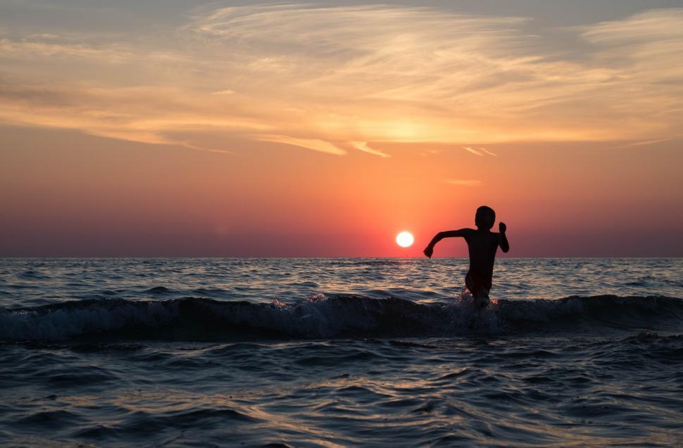 Free Image of Boy Playing in Ocean during Sunset  