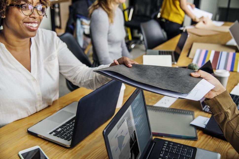 Free Image of An woman with her colleagues in a business meeting, handing over a folder  
