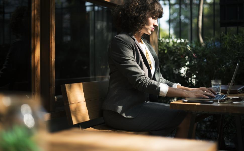 Free Image of A young woman working on her laptop at a cafe table 