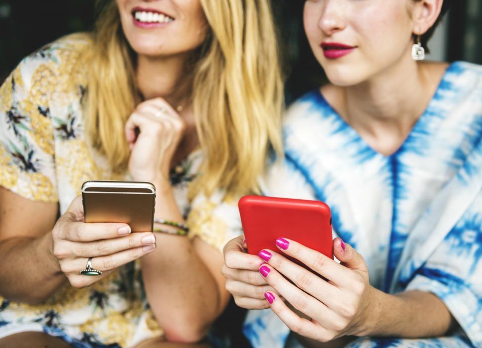 Free Image of Two young women posing for a selfie with their mobile phones 