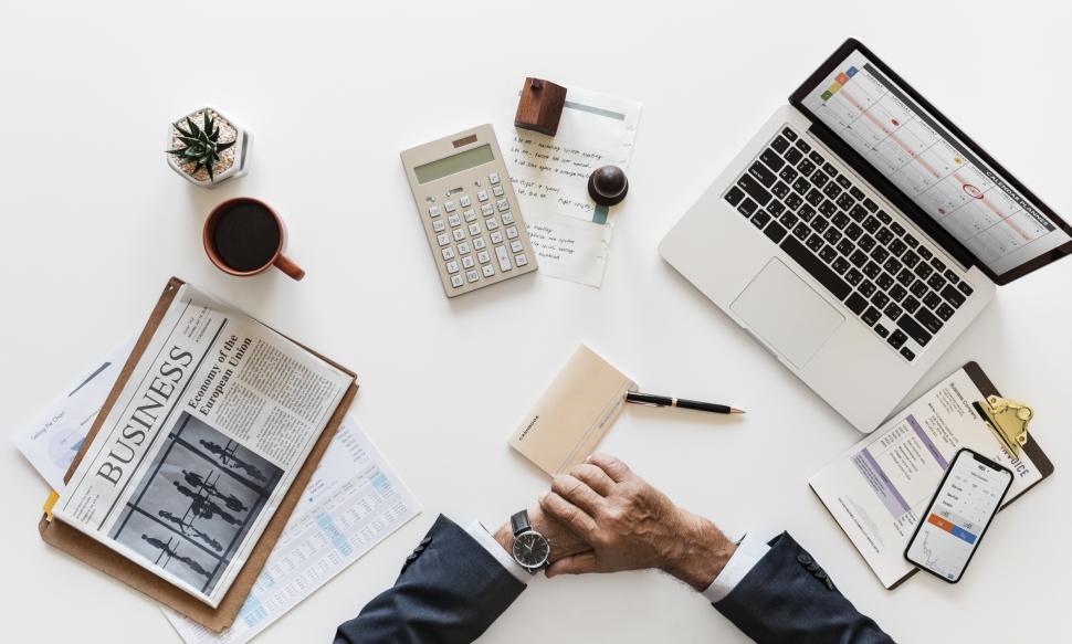 Free Image of Overhead view of a person s hands surrounded by a laptop, a coffee mug along with other items on the office table 